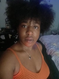 a woman in an orange top with a curly afro